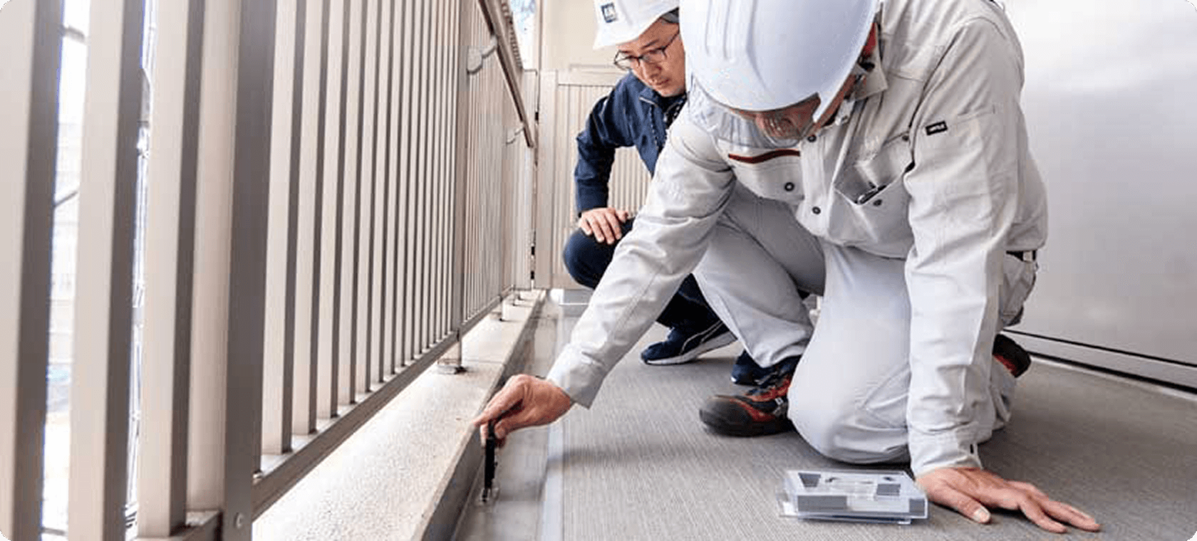 建物のバルコニーで劣化状況を調査する技術者の様子