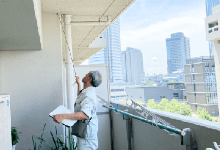 建物劣化診断を行う専門家がバルコニーで調査を行っている様子