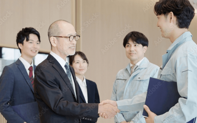 工事完了後に関係者が握手し、竣工の引き渡しを行う場面